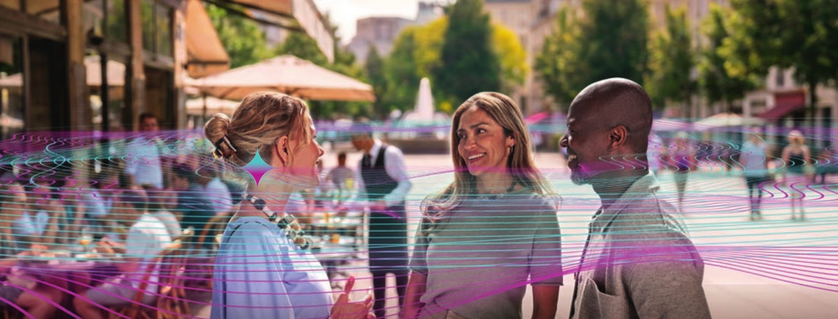 Drei Menschen im Gespräch auf einem sonnigen Platz, darüber visualisierte Schallwellen