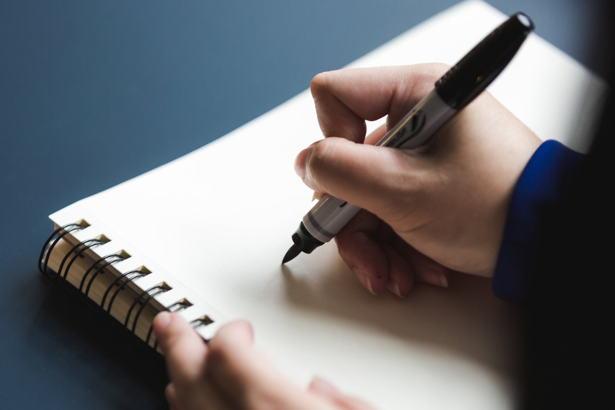 Hand schreibt mit einem Filzstift in ein Notizbuch